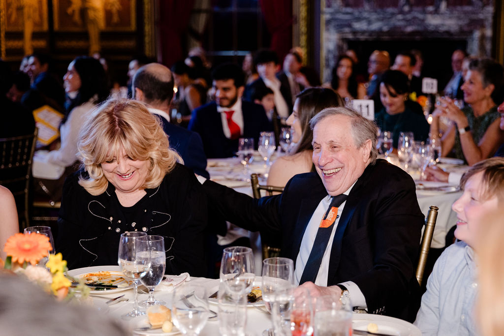 Dr. and Mrs. Lublin seated at their table, laughing during the stand up comedy set